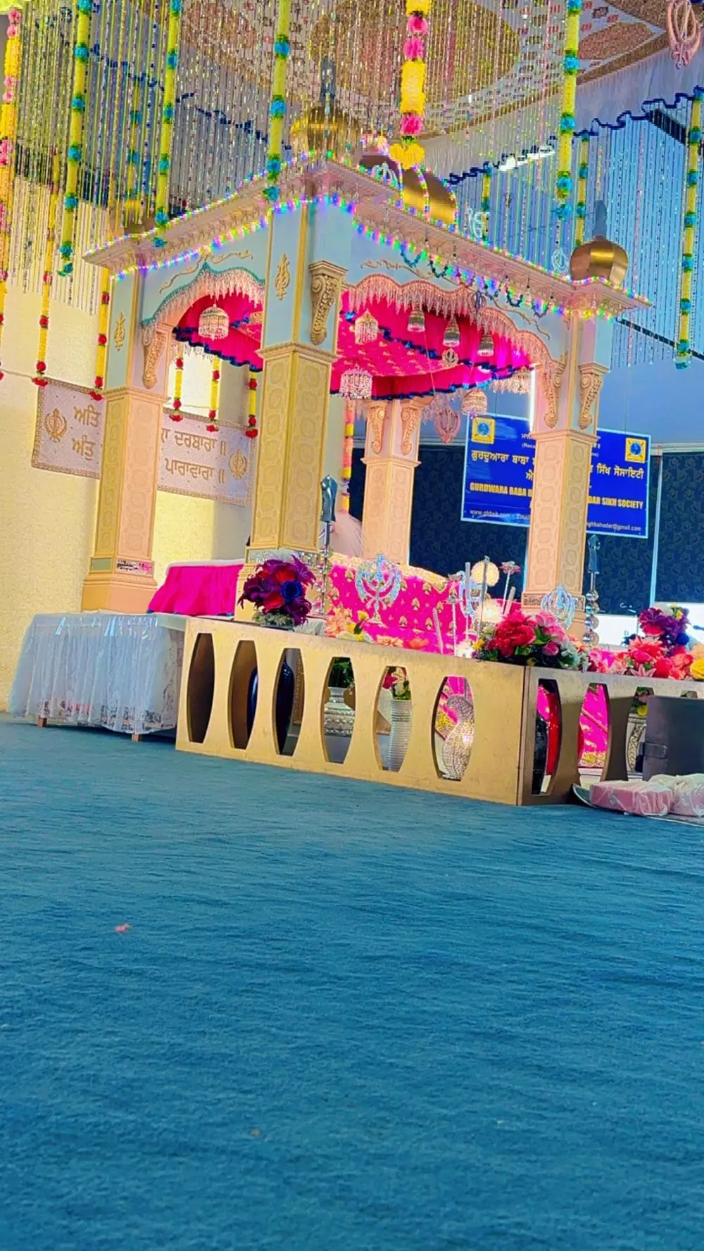 Side view of the main prayer platform with pink and blue decorative cloth and flower arrangements.