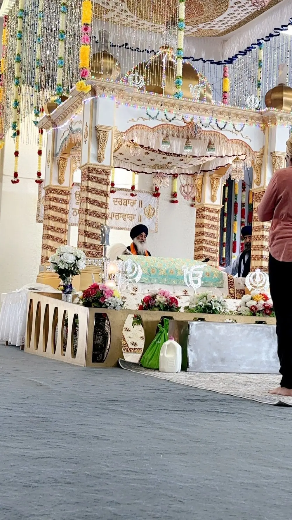 Close view of a granthi seated behind the decorated palki.