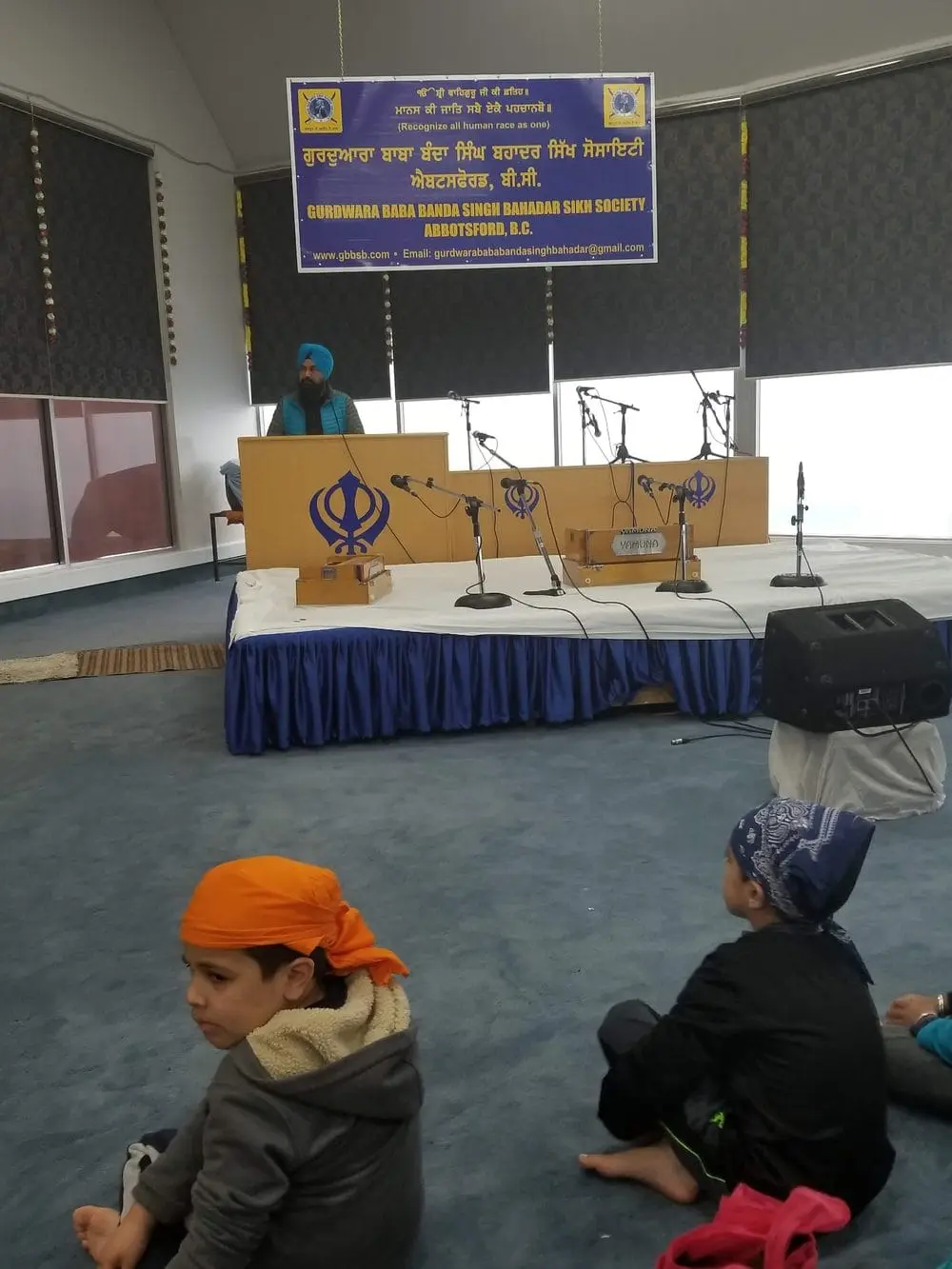 Side stage setup with speakers, podiums, and seated visitors.