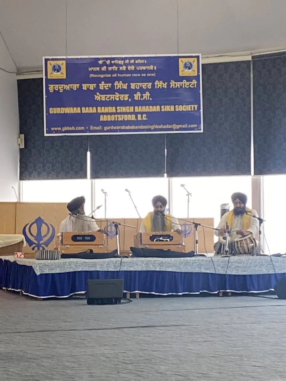 Kirtan musicians seated at the front stage with instruments.
