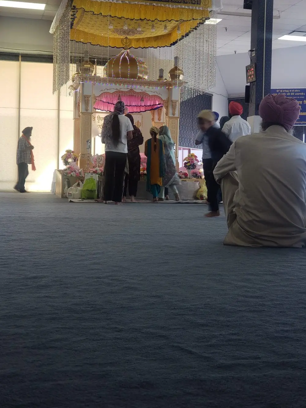 Congregants seated on the carpet during a service in the prayer hall.