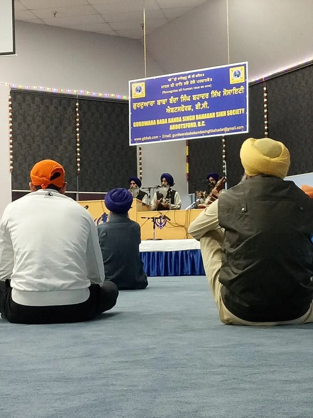 Worshippers seated and facing the stage during Kirtan.