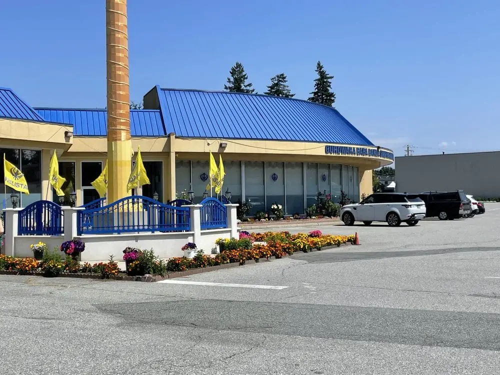 Exterior entrance area with blue-roof building and parking.