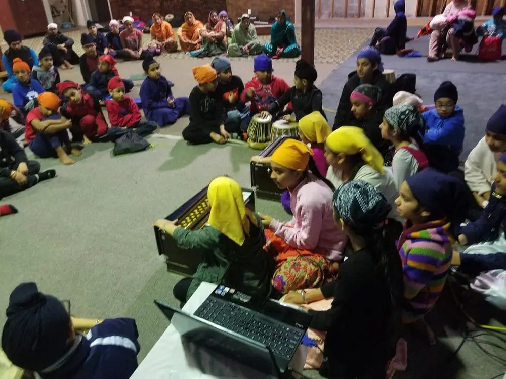 Children seated together during a community program in the hall.