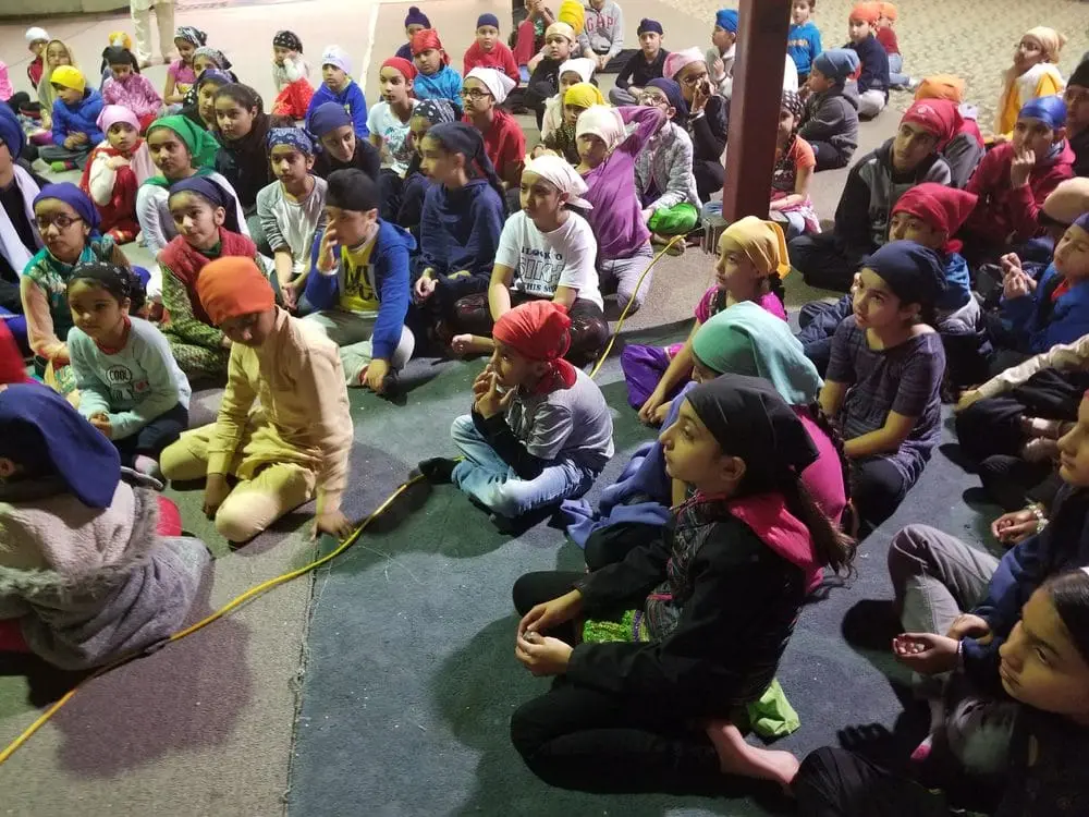 Large congregation seated on carpet for a community gathering.