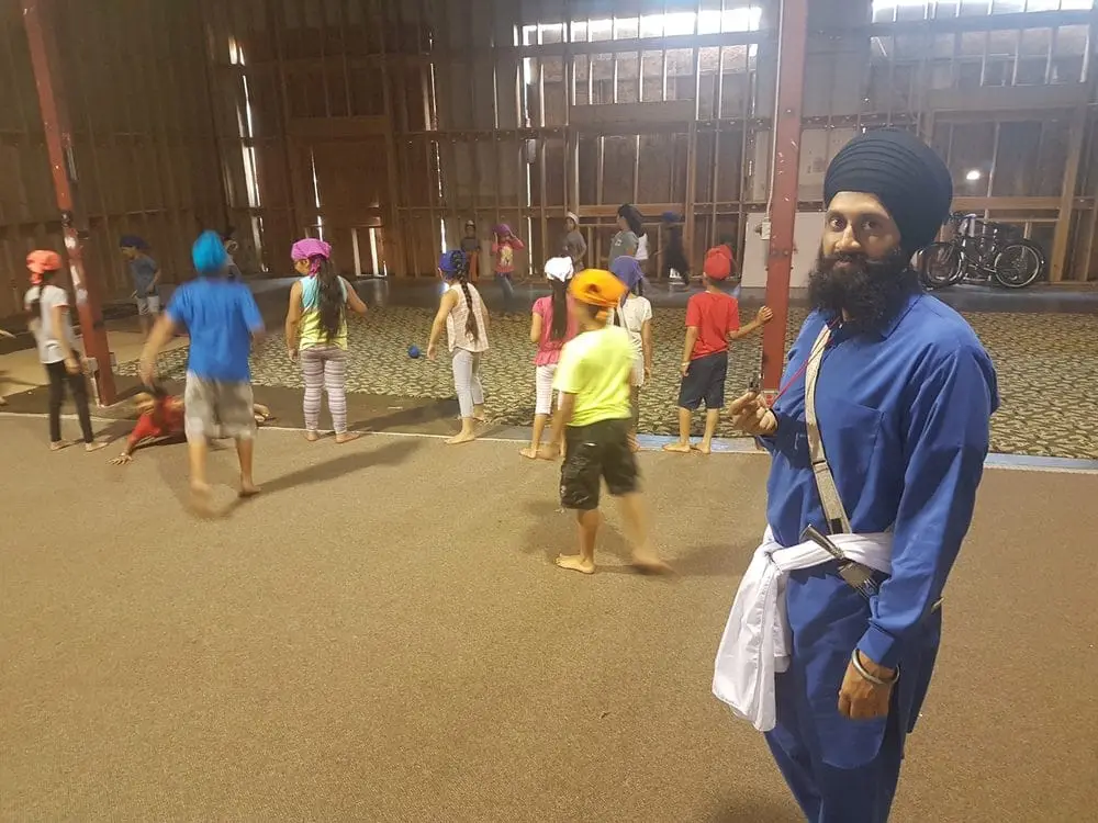 Volunteer in blue standing as children move through the hall.