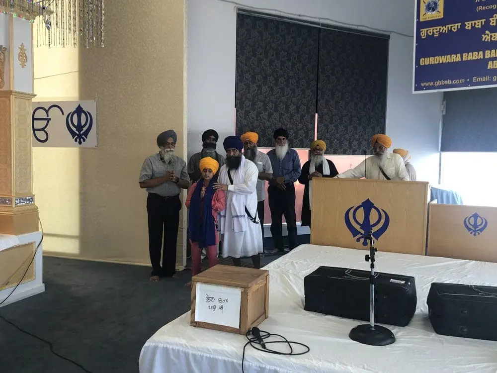 Small group standing near a microphone stand and stage.