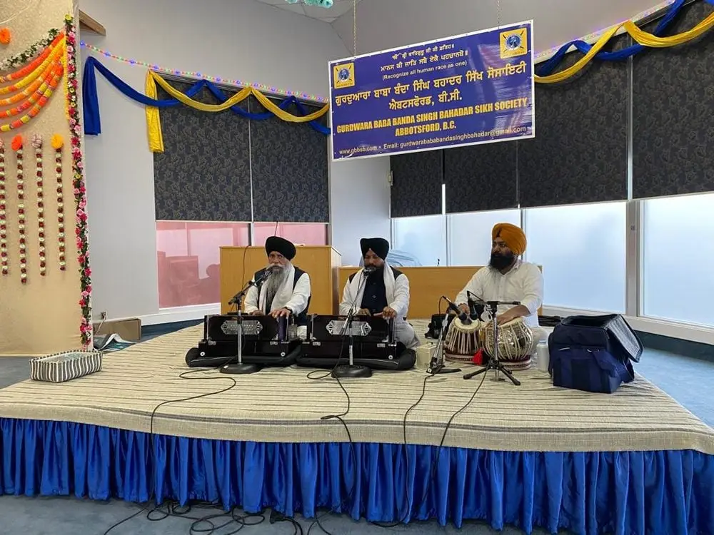 Kirtan group performing with harmonium and tabla instruments.