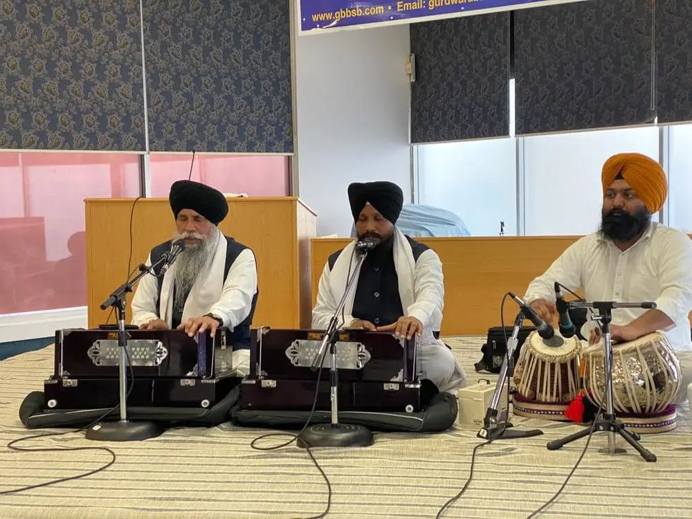 Closer view of three Kirtan musicians seated at the front.