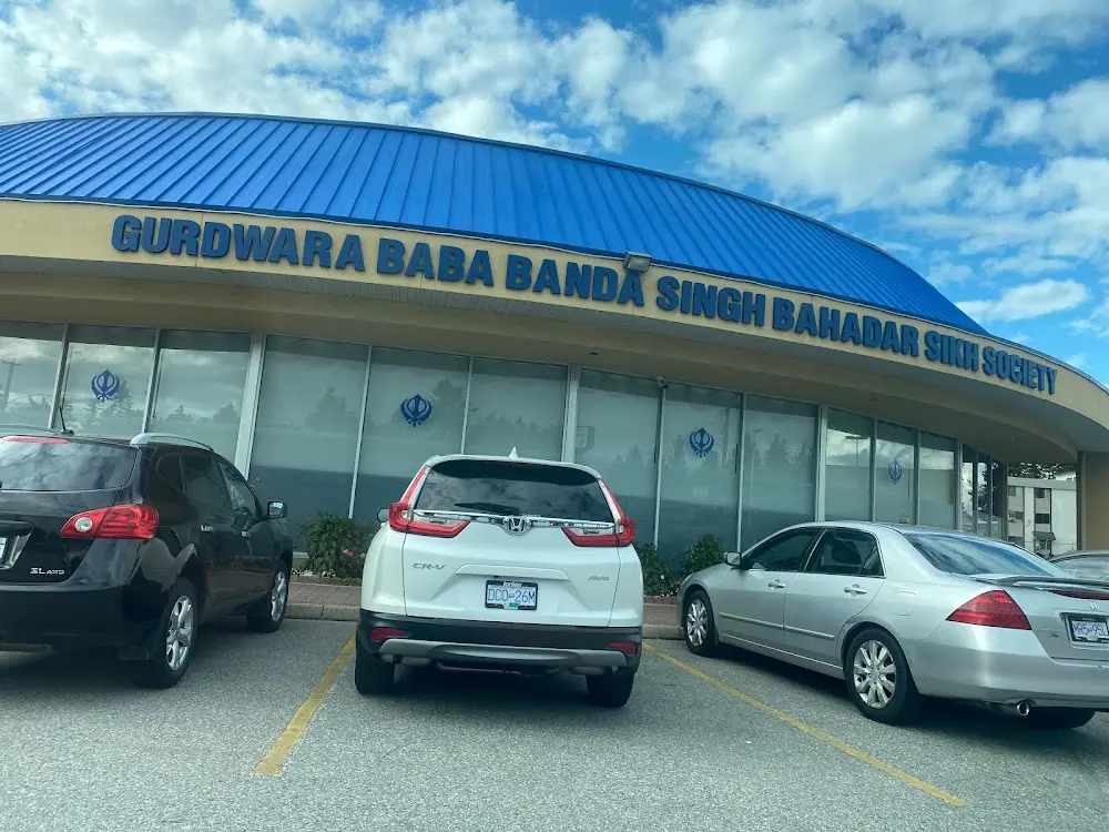 Exterior storefront sign of the Gurdwara with parked cars.