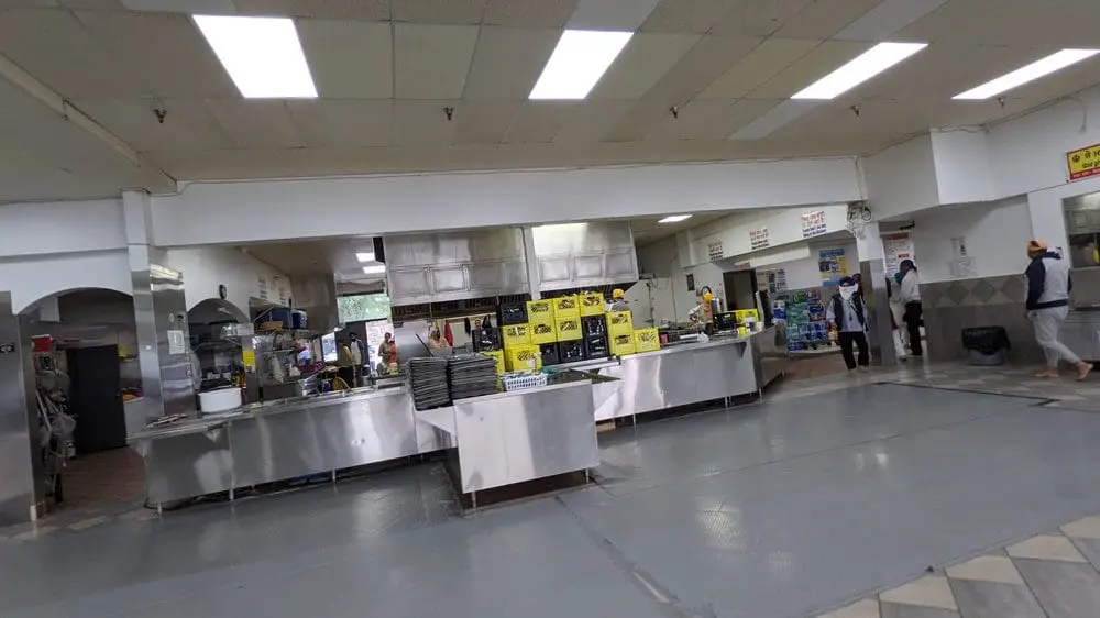 Langar hall interior with serving counters and kitchen area.