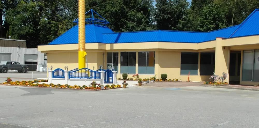 Exterior side view of the blue-roof building and Nishan Sahib.